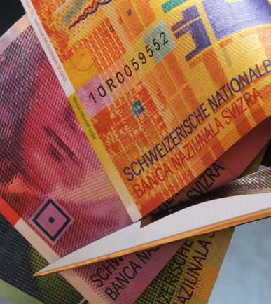 Eine Schere setzt an Schweizer Banknoten an